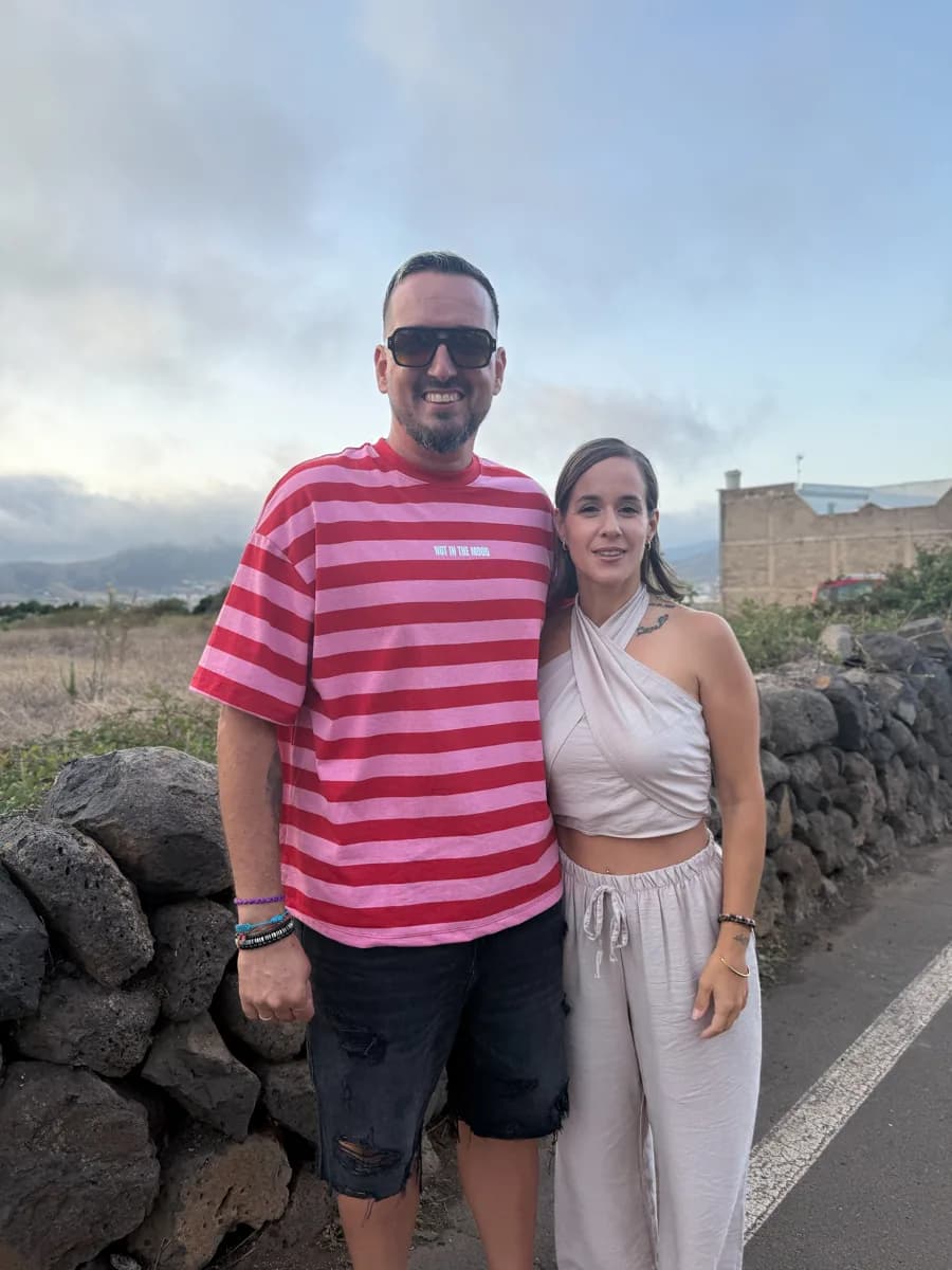Jonay y Joana, sonrientes, junto a un muro de piedra